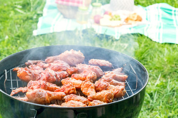 Summertime picnic in the courtyard - Cooking chicken wings on a round grill close up