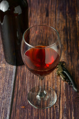 Glass of red wine over rustic, wooden textured table. Dark photo.