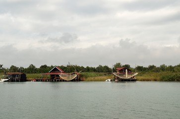 Fototapeta na wymiar Bojana island, Montenegro: Small wooden houses and restaurants on the riverbank of the Ada Bojana river near Ulcinj