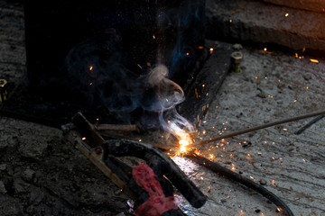 Welding of steel on the cement floor of the nut and sat steel frame. With a lot of flashes.