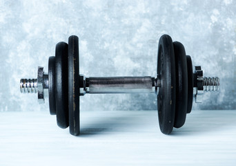 Black heavy dumbbell on rustic wooden background. Fitness or bodybuilding background  Copy space. 