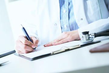 Fototapeta premium Female medicine doctor hand holding silver pen writing something on clipboard close-up. Ward round, patient visit check, medical calculation and statistics concept.