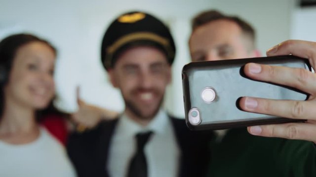 Happy couple making selfie with pilot at airport lounge. Cinematic shot on RED camera.