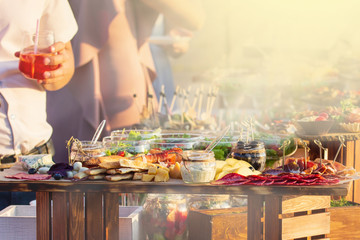 Beautifully decorated catering banquet table with different food snacks and appetizers with sandwich at sunny day