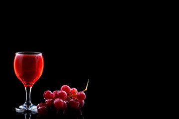 Wine glass and red grapes with drops on blak backgound. Space fot text menu