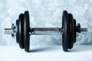 Black heavy dumbbell on rustic wooden background. Fitness or bodybuilding background  Copy space. 