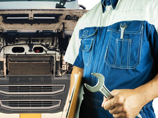 truck maintenance and repairing. Professional auto mechanic holding wrench with semi truck open the...