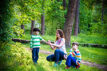 Young woman mother applying insect repellent to her two son before forest hike beautiful summer day or evening. Protecting children from biting insects at summer. Active leisure with kids