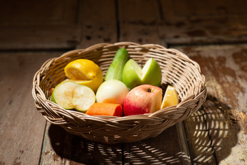 mixed fruit in weave wood basket on wooden table with morning light front view stock photo