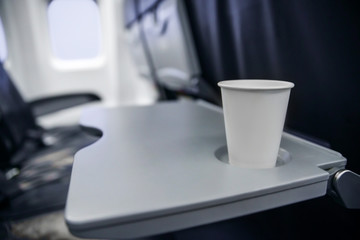 plastic cup on the table in the plane during the flight. alcohol consumption on board