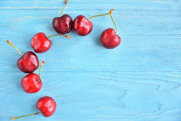 Dark red juicy organic cherries with selective focus on blue wooden background. Red sweet cherry on textured table. Cherries flat lay with empty space for text. Ripe cherries background. Summer fruits