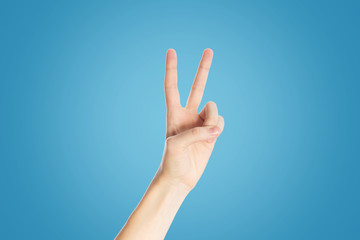 Positive gesture on a blue background. Hand show viktory sign, close up