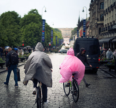 Couple cycling in Oslo's main streat wearing plastic rain ponchos
