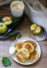 Homemade apple fritters with sour cream, coffee and green apples on a wooden background. Rustic style.