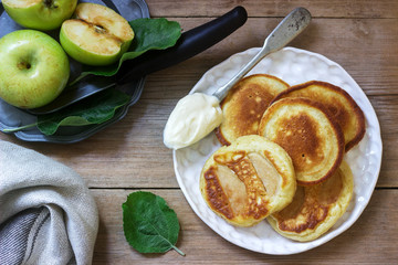 Homemade apple fritters with sour cream, coffee and green apples on a wooden background. Rustic style.