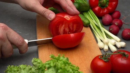 Man's hands cutting tomato on the wooden desk. Vegetables and healthy food