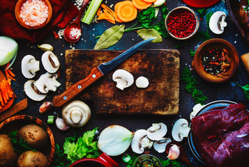 Fresh organic vegetables, ingredients, spices and meat for cooking soup on vintage kitchen table background with rustic wooden cutting board. Top view, place for text.