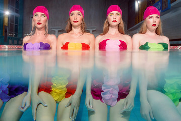 four beautiful amazing slim young stylish girls in colorful swimming suits and pink swimming hats...