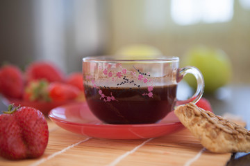 a cup of beautiful black English tea for breakfast with strawberries and cookies.