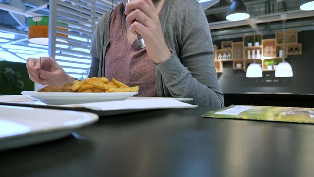 Paris, France - Circa 2019: Woman inside IKEA food restaurant eating delicious French fries and Swedish meatballs 