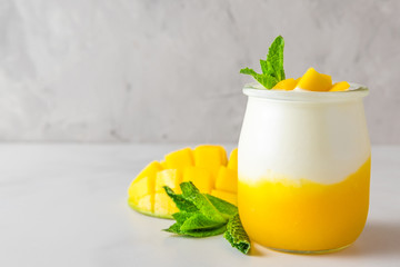 fruit mango yogurt with fresh mint in a glass over concrete background. healthy breakfast