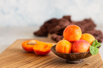 Delicious ripe apricots in a wooden bowl on a wooden cutting board. 