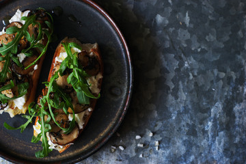 Homemade bruschetta with mozzarella, mushrooms and arugula top view space for text 