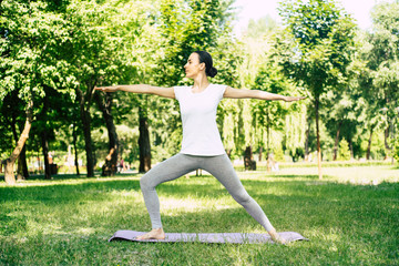 Beautiful young woman doing yoga in park. Relaxing and meditating while being surrounded by nature in summer park