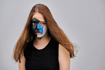Photo portrait face art of a beautiful young pretty girl with dark red hair on a gray background in a black sweater. It stands directly in front of the camera in various poses. Made in a studio.