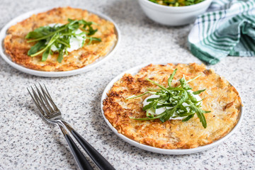 Potato rosti with corn and rocket salad served on a gray background. Traditional swiss dish