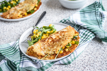 Potato rosti with corn and rocket salad served on a gray background. Traditional swiss dish