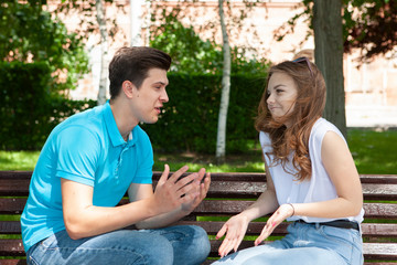 Conflicted couple not talking to each other seated on a wooden bench in park