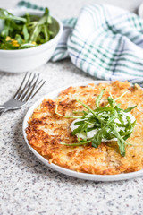 Potato rosti with corn and rocket salad served on a gray background. Traditional swiss dish