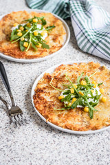 Potato rosti with corn and rocket salad served on a gray background. Traditional swiss dish