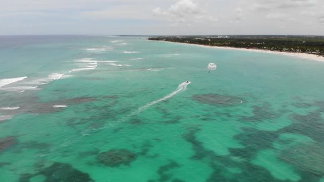 Aerial drone shot of Dominicana, an island in the Caribbean with people parasailing and resorts in the background
