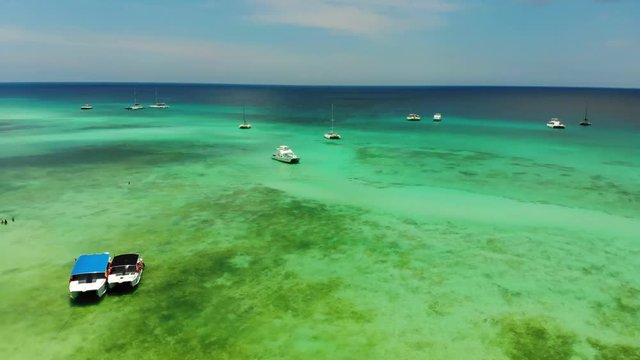 Aerial wide angle panning shot of small fishing and motor boats anchored at Dominicana, an island in the Caribbean