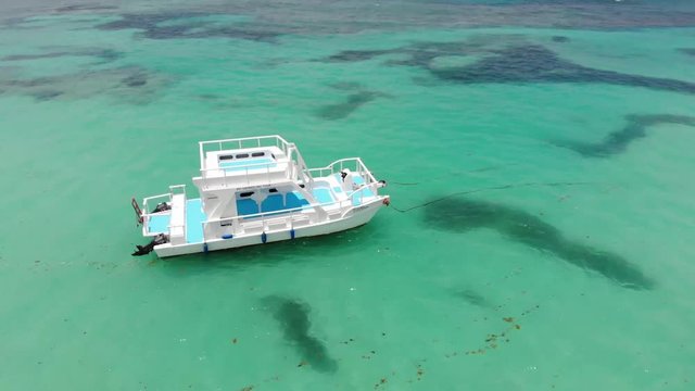 Aerial revolving shot of a boat anchored in shallow waters in Dominicana, an island in Caribbean