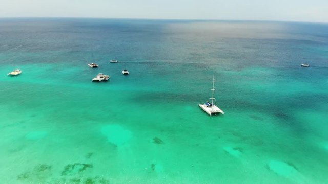 Aerial wide angle panning shot of small fishing and motor boats anchored at Dominicana, an island in the Caribbean