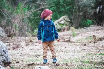 A boy with a backpack is walking along a forest path.