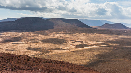 View over the vast deserted volcanic landscape of the Island of La Graciosa in Canary, Spain, with volcano crater silhouettes in the distance. Scenic mars like background.