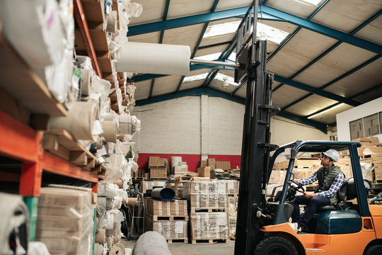 Forklift driver taking stock off shelves in a large warehouse
