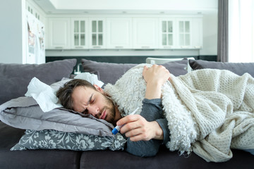A sick man looks at a thermometer