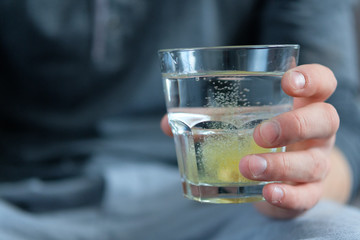 The tablet is dissolved in a glass of water, which holds a man