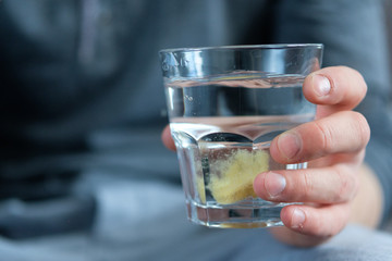The tablet is dissolved in a glass of water, which holds a man