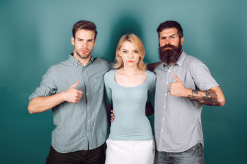 Love triangle concept. Blonde girl and two guys in casual clothes looking at the camera.