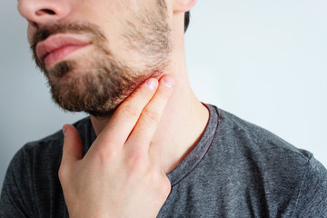 Fototapeta premium Photo of an attractive man, holds his hand on his wrist and neck, checks the pulse or heart rate, cares about his health, has a heartbeat, models on a white background. Pulse evaluation concept