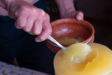 The shifting of honey from a larger container into a bowl.