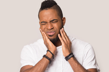 Millennial black man suffering from sudden strong toothache