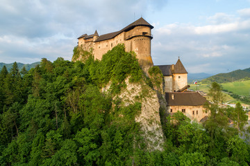 Fototapeta na wymiar Orava castle - Oravsky Hrad in Oravsky Podzamok in Slovakia. Medieval stronghold on extremely high and steep cliff. Aerial view in summer at sunset