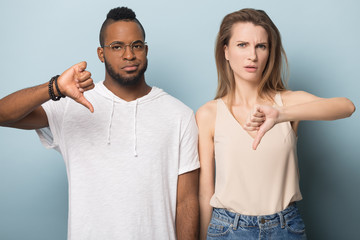 Millennial family couple showing thumbs down gesture.
